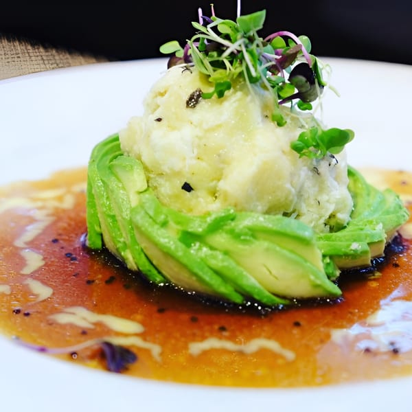 Tsuru Sushi's avocado salad with microgreens and a savory sauce on a white plate.