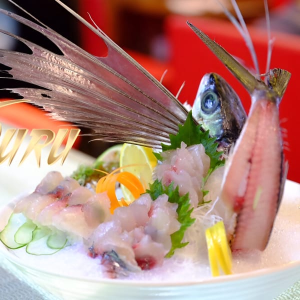 Tsuru Sushi Asian Cuisine's sashimi dish with a whole fish head and tail, garnished with lemon and cucumber.