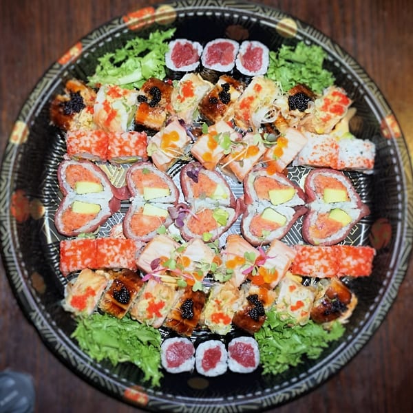 A large platter of Tsuru Sushi's assorted sushi rolls, including tuna, salmon, and avocado.
