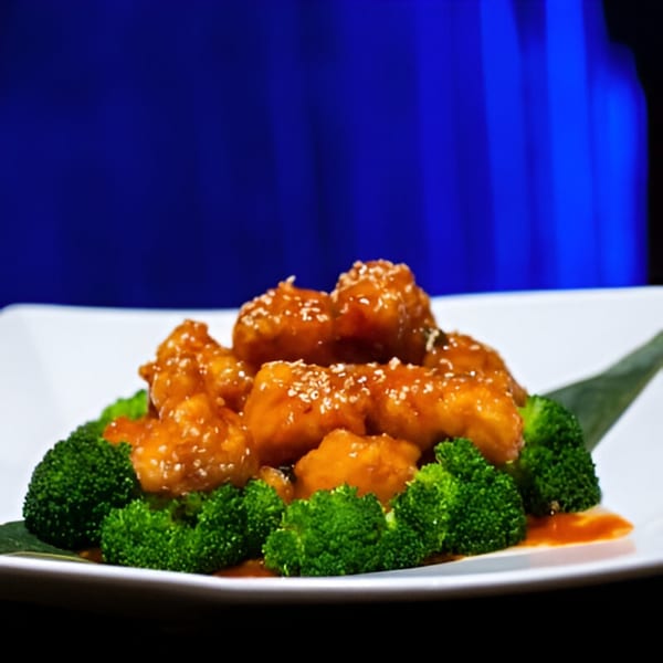 Tsuru Sushi's orange chicken with sesame seeds and broccoli on a white plate.